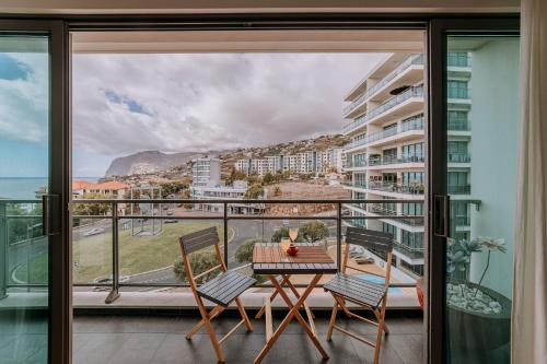a balcony with a table and chairs and a view of the ocean at Cozy T2 with Ocean View in Funchal