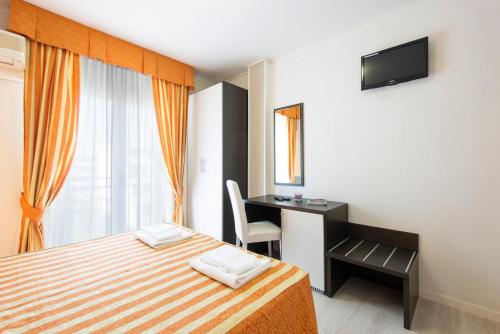 a bedroom with a bed and a desk and a television at Hotel Columbus in Caorle