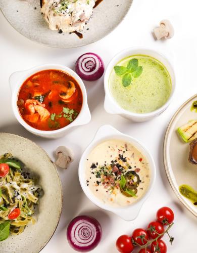 a white table topped with bowls of soup and vegetables at Oasis Residence in Bishkek