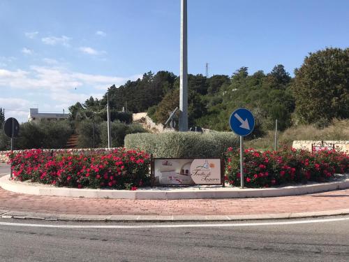 a roundabout with red flowers and a blue sign at Trullo Di Tagaro in Locorotondo