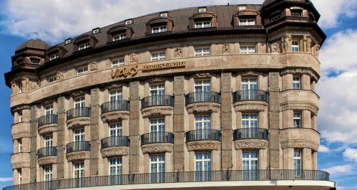 ein großes Backsteingebäude mit einem Balkon in der Unterkunft Victor's Residenz-Hotel Leipzig in Leipzig