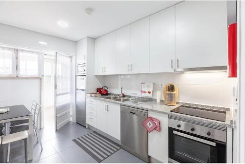 a white kitchen with white cabinets and a sink at Old Market Apartment in Guimarães