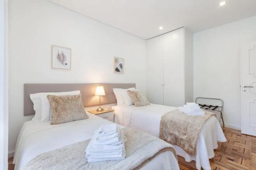 two beds in a room with white walls at Old Market Apartment in Guimarães