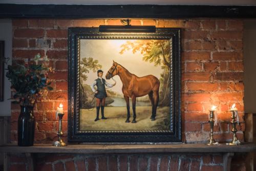 una pintura de un hombre y un caballo en una pared en The Horse and Groom Inn, en Chichester