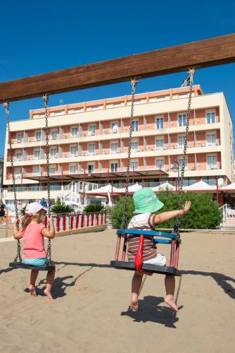 two children playing on a swing at the beach at Hotel Columbus in Caorle