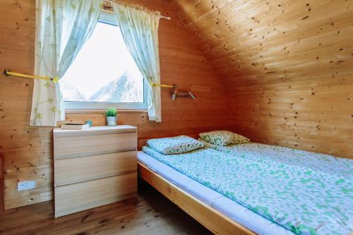 a bed in a wooden room with a window at Ośrodek domków letniskowych Sztorm in Chłopy