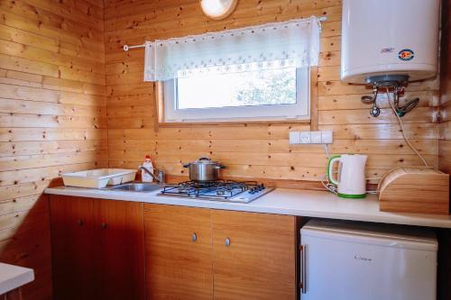 a small kitchen with a stove and a window at Ośrodek domków letniskowych Sztorm in Chłopy