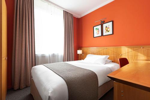 a hotel room with a bed with an orange wall at Hôtel Des Artistes in Lyon