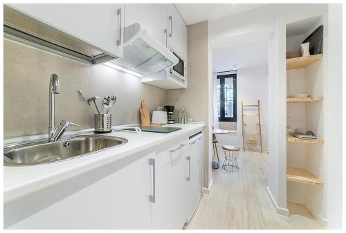 a white kitchen with a sink and a counter at Apartamentos Madrid Rio in Madrid
