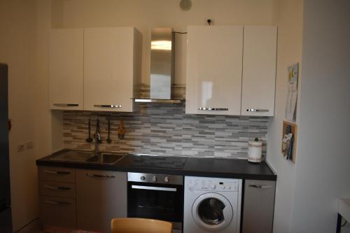 une cuisine avec des armoires blanches et une machine à laver dans l'établissement Residence Borsellino 41, à Garbagnate Milanese