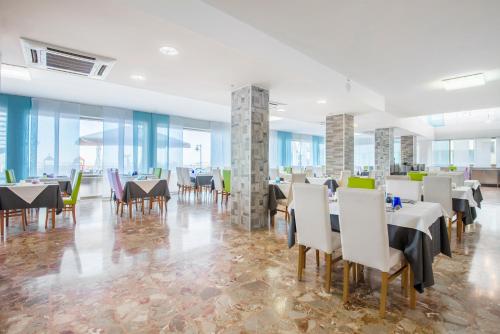 a dining room with tables and chairs and windows at Hotel Columbus in Caorle