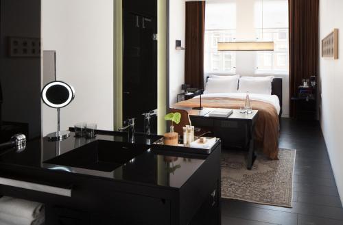a bathroom with a sink and a bed with a mirror at Sir Albert Hotel in Amsterdam
