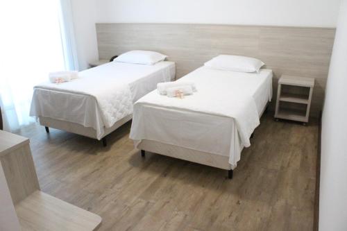two beds in a room with white sheets at Serrano Hotel in Ribeira