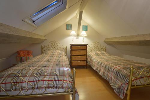 a attic bedroom with two beds and a window at Le Prieuré L´Atelier in Lanzac