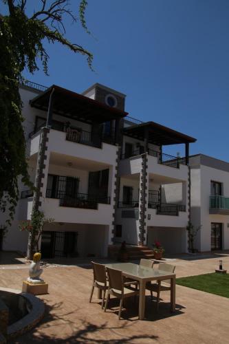 a building with a table and chairs in front of it at Orya Aparts in Gümbet