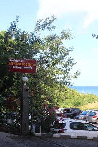 a sign for a parking lot with cars parked at BO SOLEY, studio vue mer Les Hauts de Caritan in Sainte-Anne