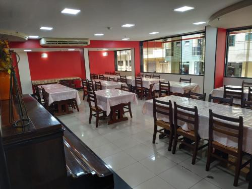 ein Restaurant mit Tischen, Stühlen und roten Wänden in der Unterkunft Hollywood Palace Hotel in Aparecida