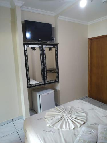 a room with a bed and a flat screen tv at Hollywood Palace Hotel in Aparecida