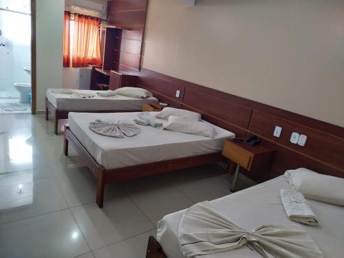 a hotel room with three beds in a room at Hollywood Palace Hotel in Aparecida