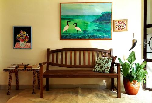 a bench in a room with a table and a painting at Pousada Dom Aquino in Campo Grande
