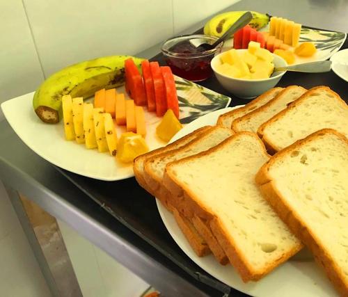 a table with two plates of bread and fruits and vegetables at DREAM Hill HOMESTAY NUWARA ELIYA in Nuwara Eliya
