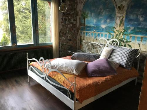 a bed with pillows on it in a room with windows at Casa toscana in Thun
