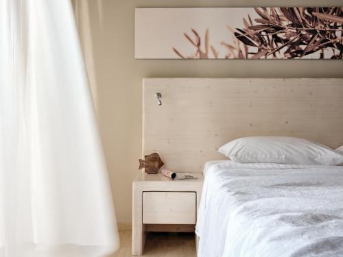 a bedroom with a white bed and a night stand at Ionian Hill Hotel in Argasi