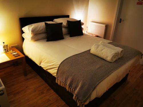 um quarto com uma cama grande com lençóis brancos e almofadas em The Cavendish Five Bells em Cavendish