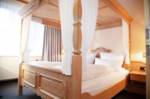 a bedroom with a four poster bed with white sheets at Hotel Lonac in Duisburg