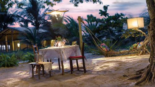 a table with chairs and a lamp in the sand at Rancho Do Peixe in Prea