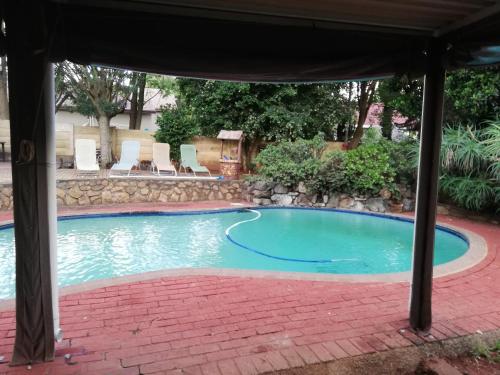 a swimming pool under a pavilion with a table and chairs at Rocky Ridge Guest House SELF Catering - No alcohol allowed in Roodepoort
