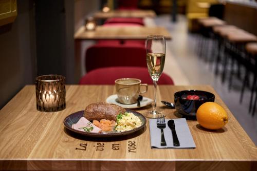 a table with a plate of food and a glass of wine at Hotel Mariënhage in Eindhoven