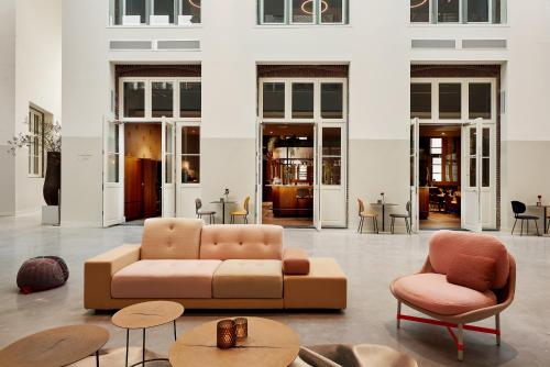 een woonkamer met een bank, stoelen en tafels bij Hotel Mariënhage in Eindhoven