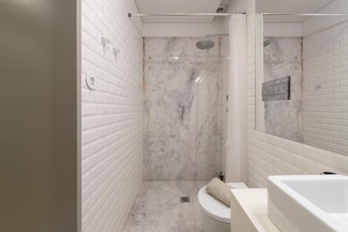 biała łazienka z prysznicem i umywalką w obiekcie LovelyStay - Stylish Central Apartment by Bolhão Market w Porto