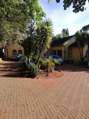 um edifício com palmeiras e uma entrada de tijolos em Rocky Ridge Guest House SELF Catering - No alcohol allowed em Roodepoort