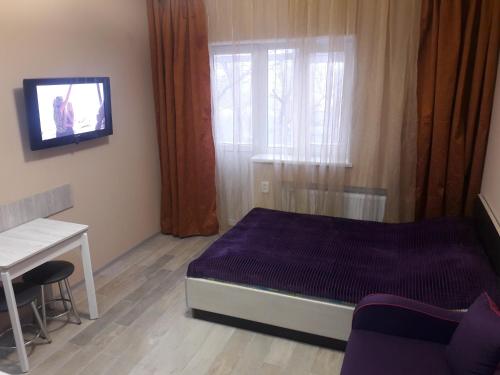a bedroom with a bed and a desk and a tv at Apartments near Metalist Stadium in Kharkiv