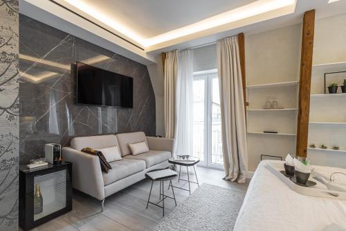 a living room with a couch and a tv on a wall at Le Dortoir Boutique Suites in Nice