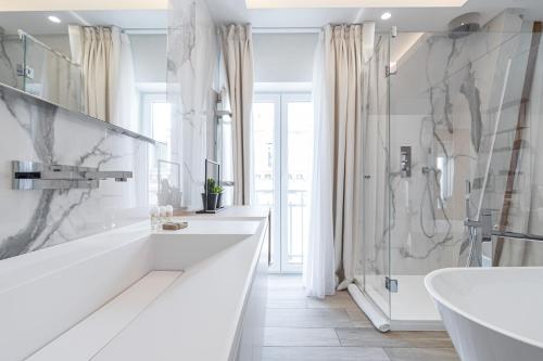 a white bathroom with a tub and a sink at Le Dortoir Boutique Suites in Nice