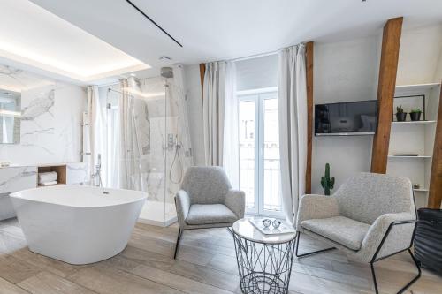 a bathroom with a bath tub and two chairs at Le Dortoir Boutique Suites in Nice