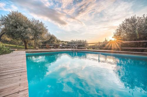 a swimming pool with a sunset in the background at Alpaca country house in Pontedera