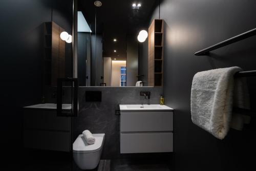 a bathroom with a sink and a toilet and a mirror at Mirabilis Apartments - Bayham Place in London