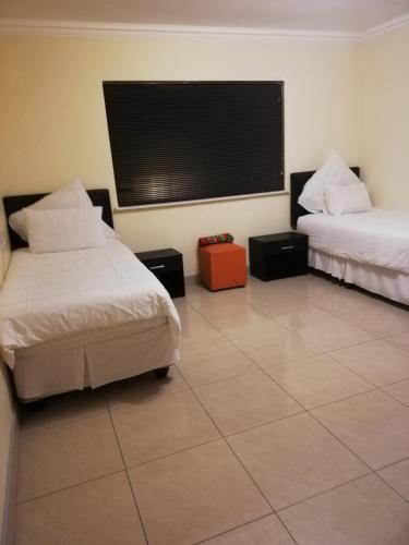a room with two beds and a flat screen tv at Rocky Ridge Guest House 2 SELF CATERING - No Alcohol allowed in Roodepoort