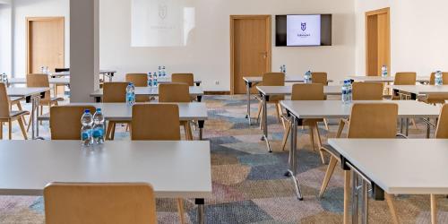an empty classroom with white tables and chairs at Hotel Termalny in Uniejow