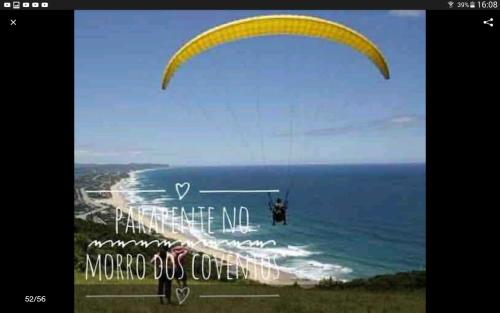 a person flying a parachute over the ocean at Studio confortavel - ate 4 pessoas in Araranguá
