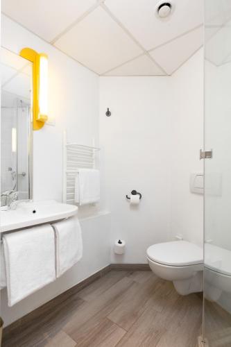 a white bathroom with a toilet and a sink at ibis budget Warszawa Centrum in Warsaw