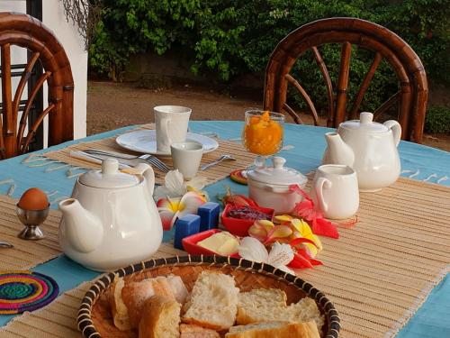 een tafel met een blauwe tafeldoek met brood en theepotten bij Villa Malandy Appart Hôtel Triplex in Madirokely