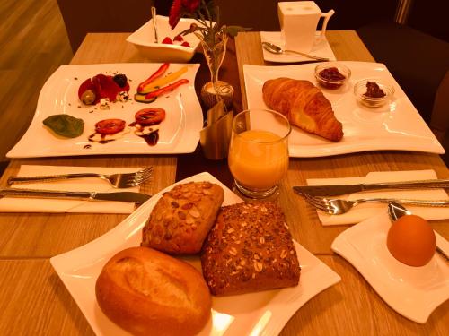 two plates of food on a table with bread and orange juice at Hotel Glinde in Hamburg