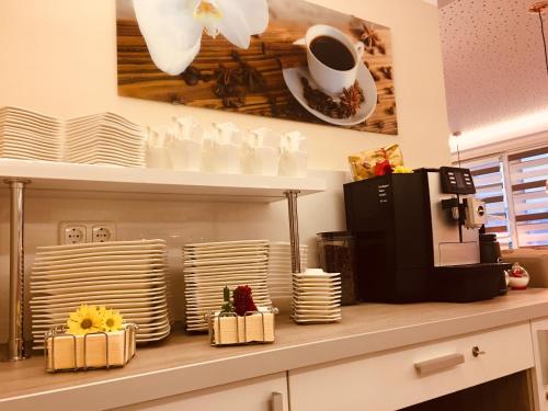 a kitchen counter with plates and a coffee maker at Hotel Glinde in Hamburg