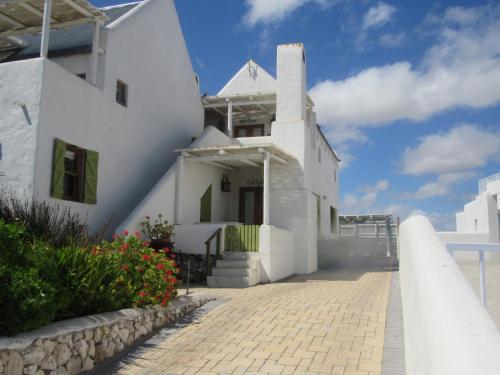 une maison blanche sur la plage avec un sentier dans l'établissement Marlyn and Dolfyn Self Catering, à Paternoster