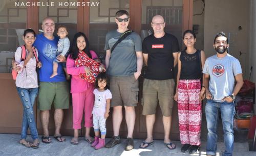 a family posing for a picture in front of a house at Nachelle Homestay in Berastagi